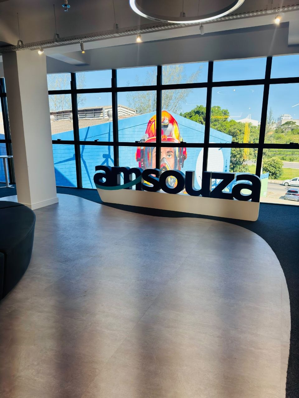 Entrada corporativa com logo Amsouza aplicado no vidro e mural externo visível