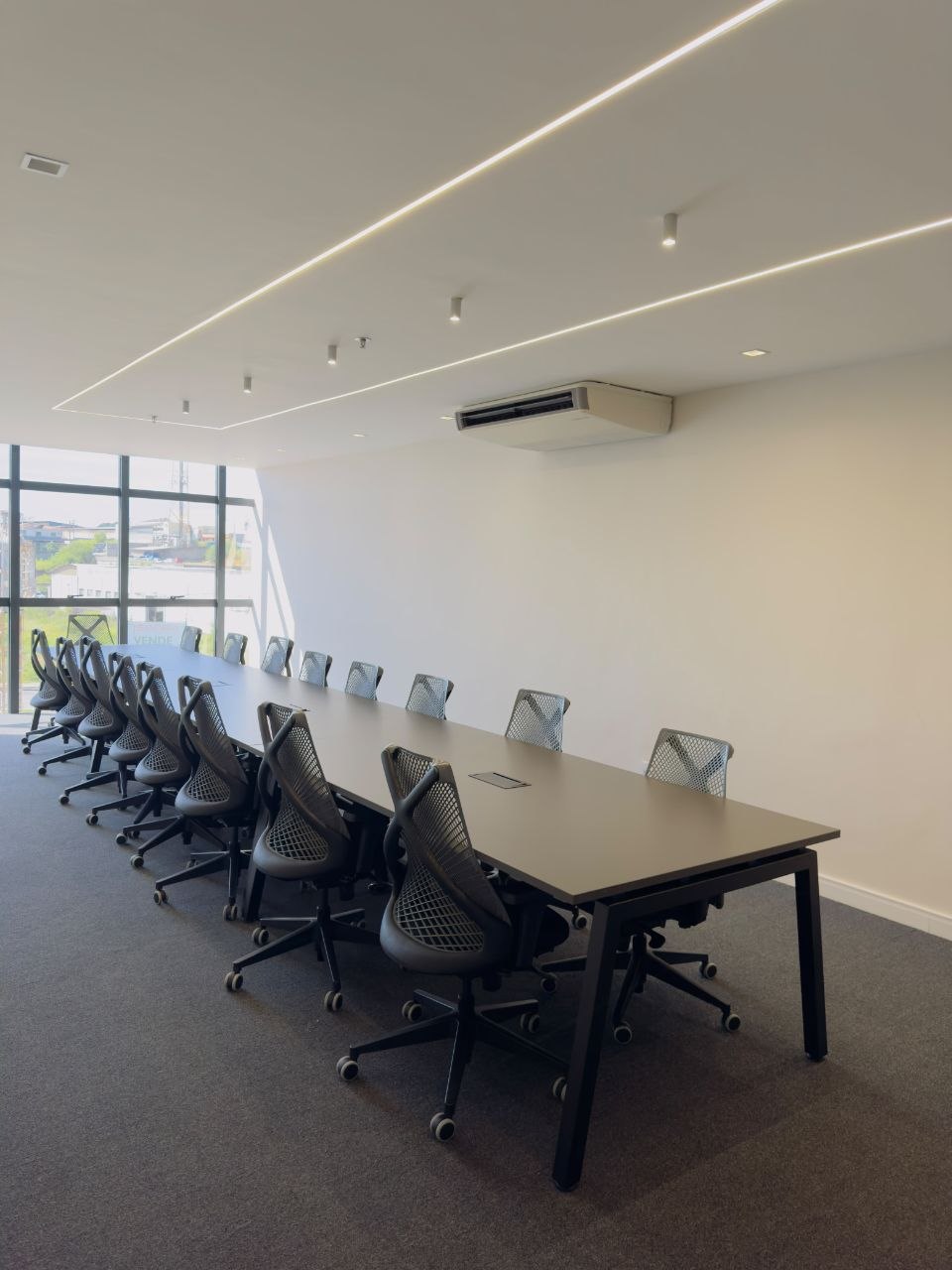 Sala de reunião ampla com mesa longa e cadeiras ergonômicas